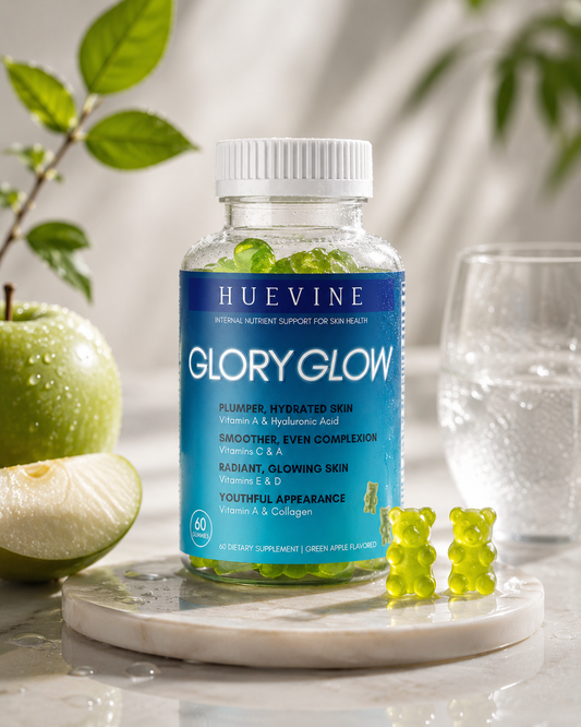 HueVine Glory Glow vitamins with green apple gummies displayed on a marble tray with fresh apple slices in a luxury wellness setting.