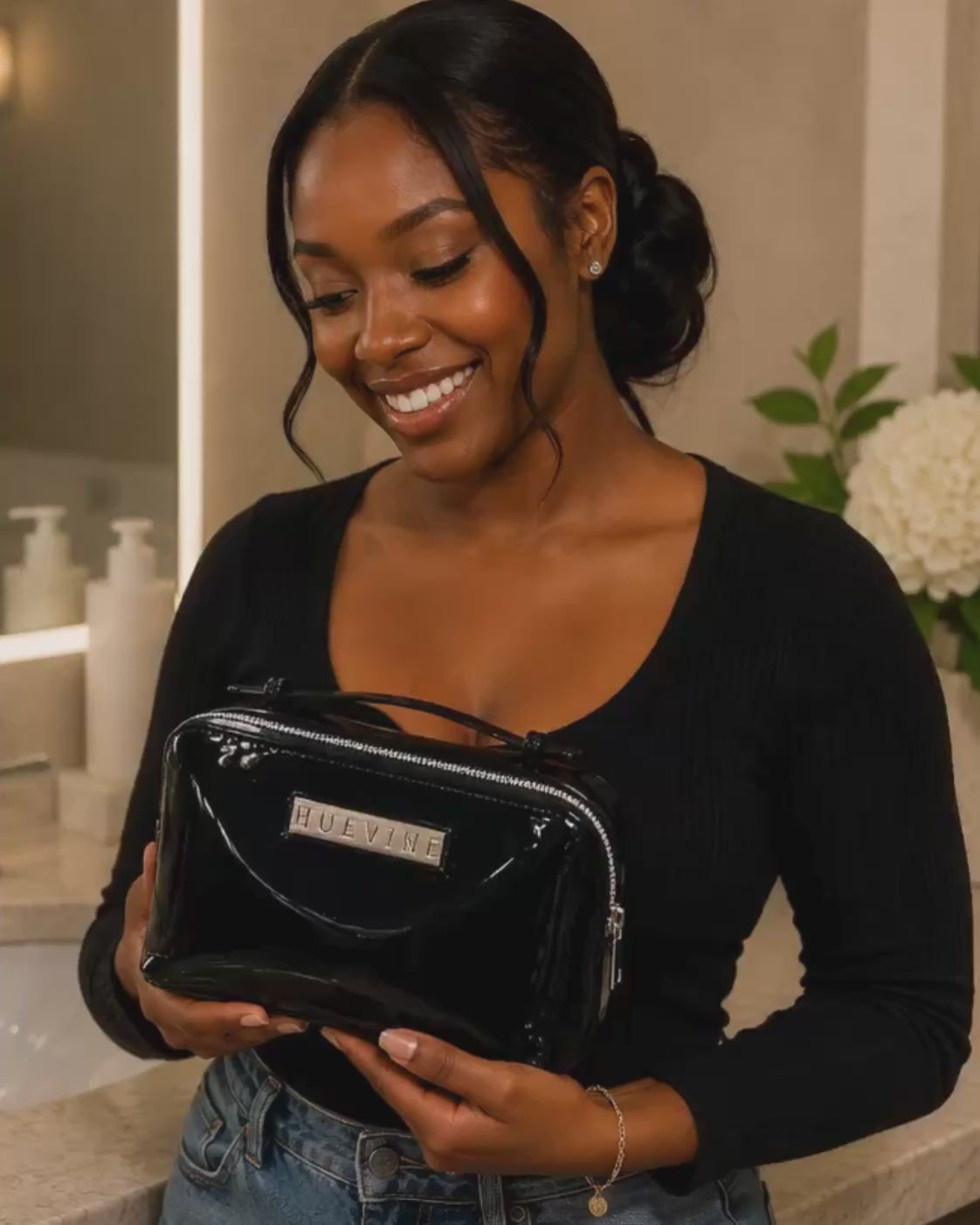 Woman holding the HueVine Glow Bag in a luxury bathroom setting.