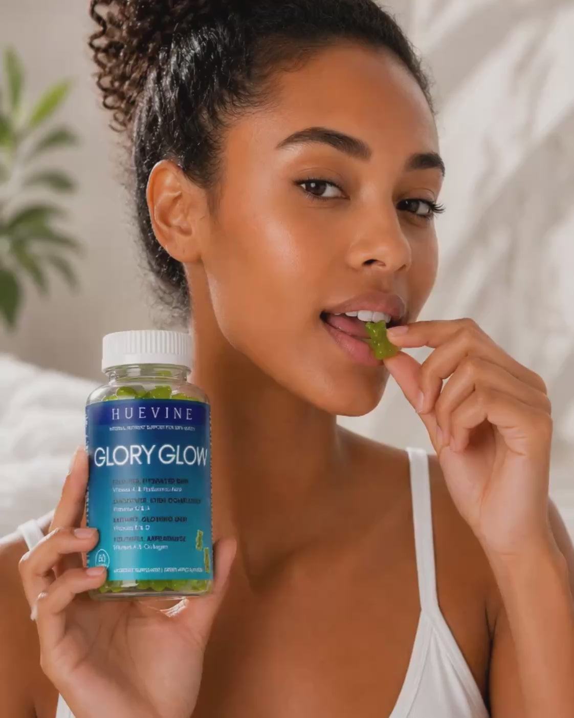 Video demonstration of a woman taking HueVine Glory Glow vitamin gummies as part of a daily wellness routine.
